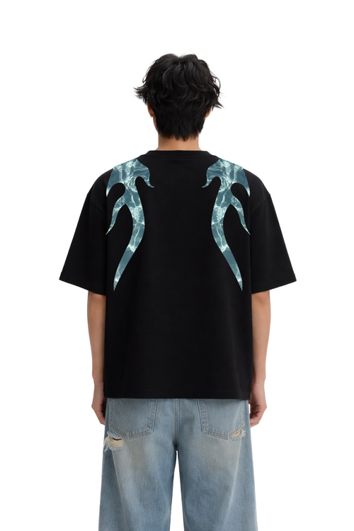 Back view of oversized black streetwear t-shirt with blue abstract flame graphic, paired with ripped jeans