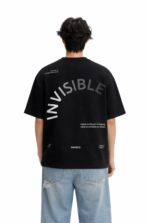 Man wearing black oversized streetwear t-shirt with 'INVISIBLE' text and blue jeans