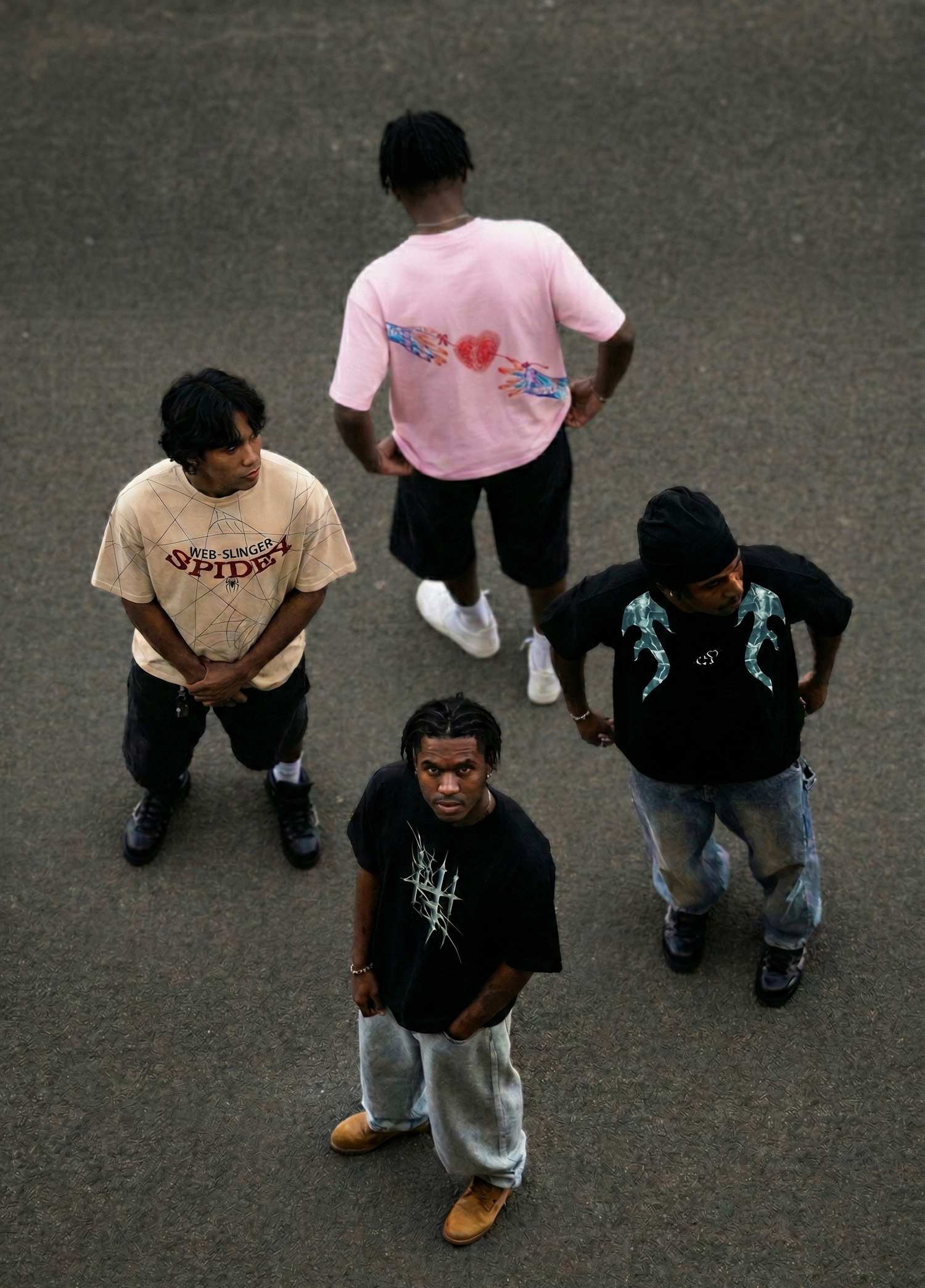 Group of four men wearing modern oversized streetwear graphic t-shirts standing outdoors