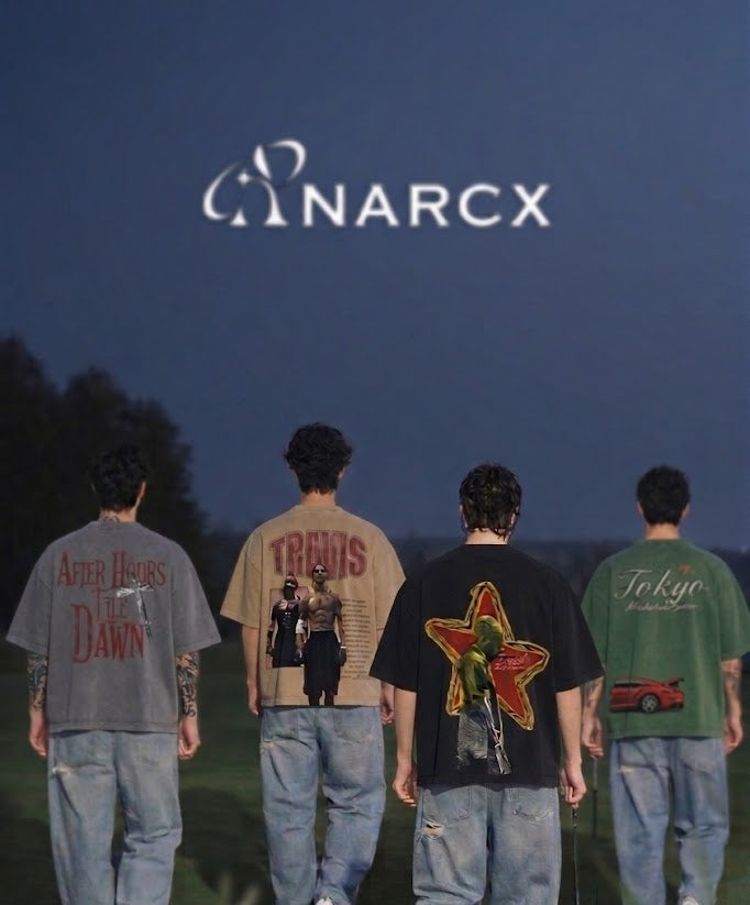 Four men in oversized streetwear graphic t-shirts and jeans outdoors at dusk