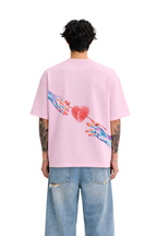Man wearing oversized pink streetwear t-shirt with colorful hand and heart graphic on back
